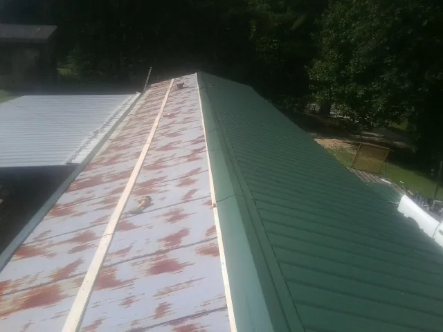 Old rusted panels beside newly installed green metal roofing — Wind Damage Roof Repair by Roofing Brothers in New Castle