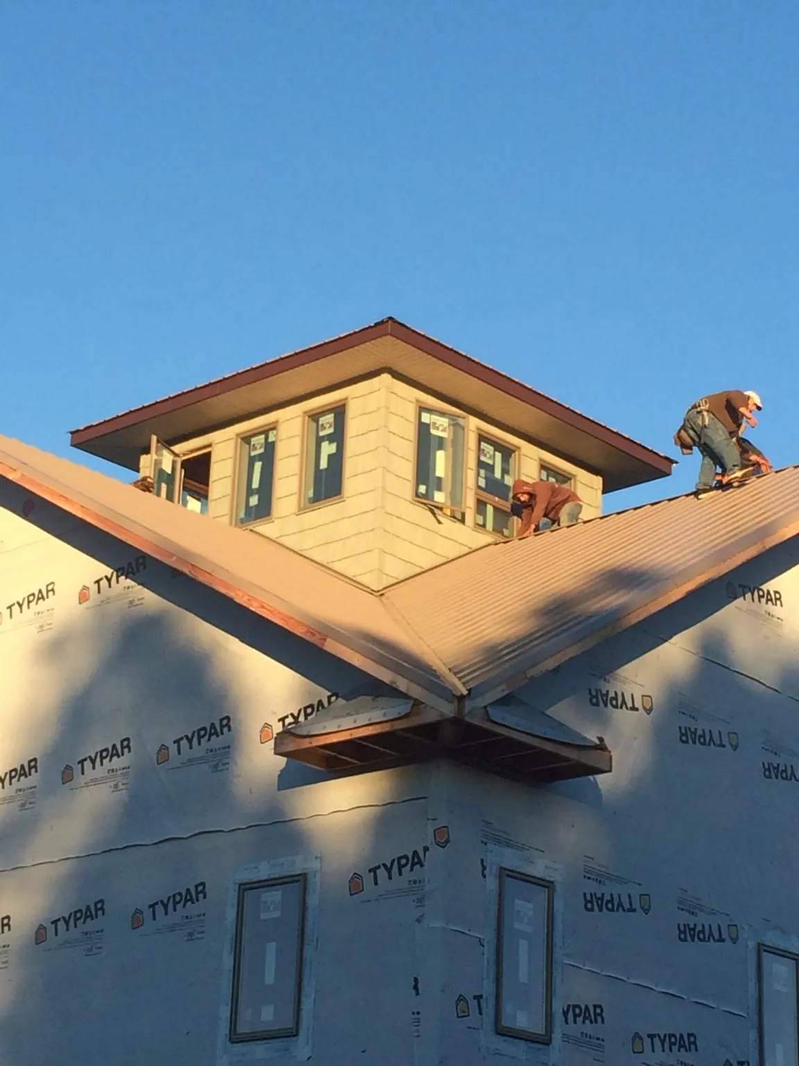 Roofers working around a rooftop cupola on a new metal roof at sunset — Roof Waterproofing in New Castle by Roofing Brothers